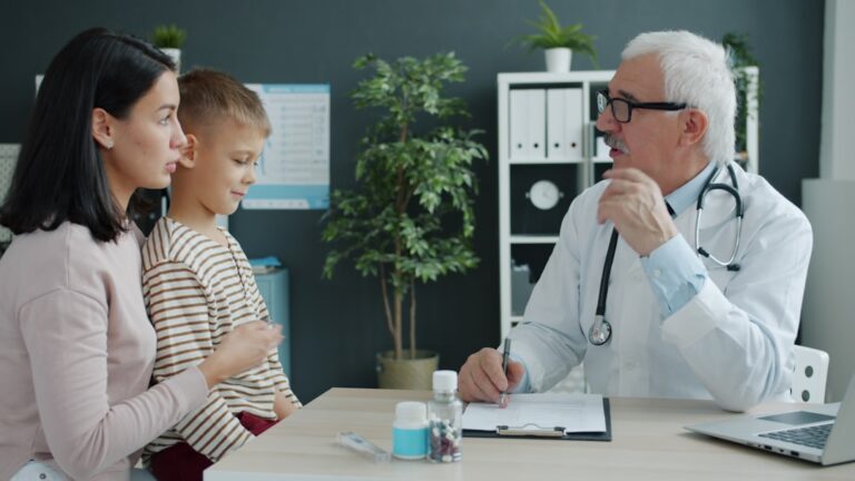 A parent and teen sitting together at a kitchen table, talking seriously in a calm home setting.